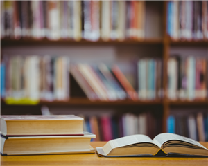 library books on a table with shelves of books in the background 